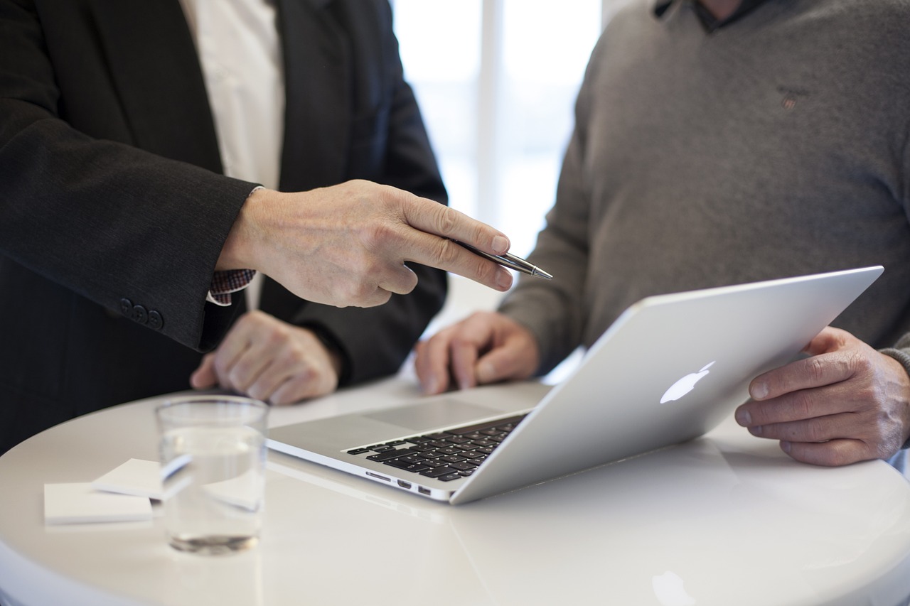 Two people are sitting at a table with a laptop.